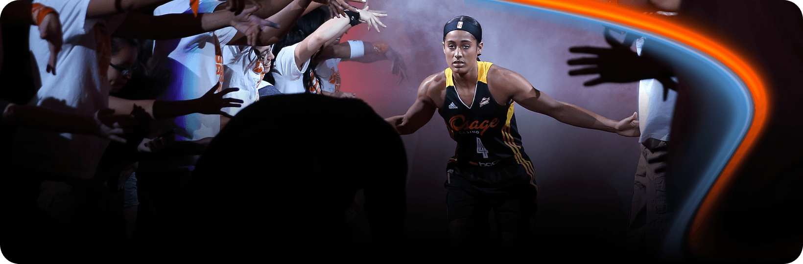 WNBA player runs onto the court through a smoke-filled tunnel, high-fiving fans reaching out from both sides